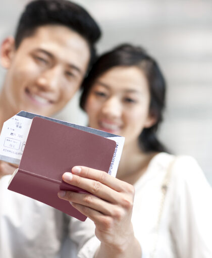 Young Chinese couple at the airport with flight tickets and passports