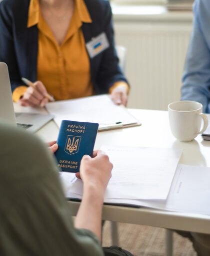 A senior woman volunteer helping Ukrainian woman to fill in forms at asylum centre.